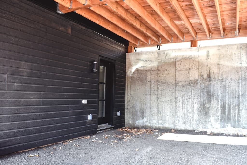 Garage of new build, wood, black siding and cement wall